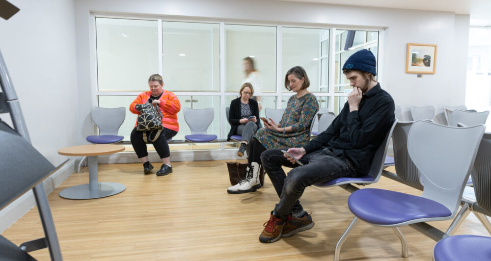 Picture of a group of people sat waiting in a waiting room