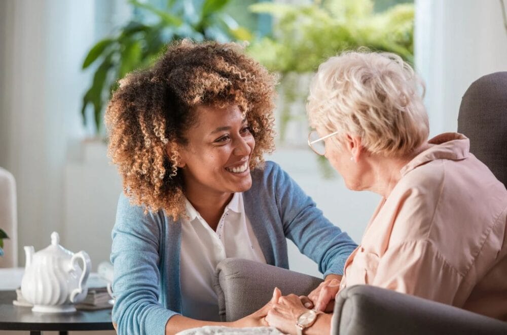 Carer holding hands of older patient