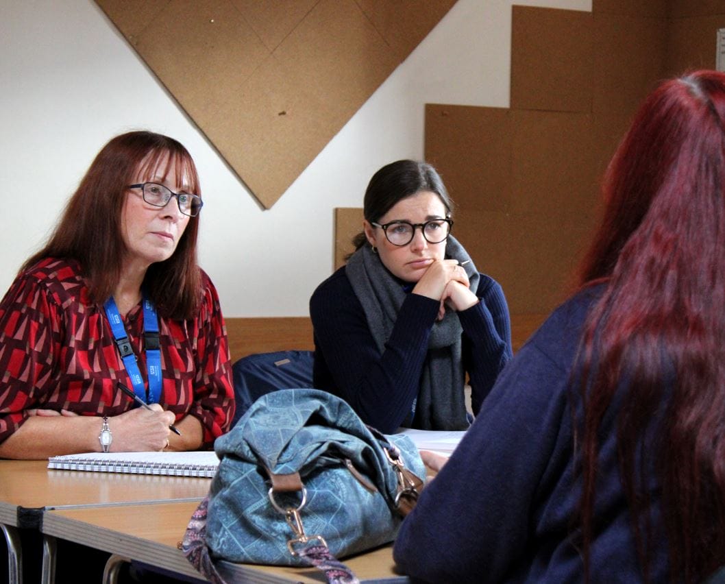 3 people sat at a table. 2 listening intently to the third person.