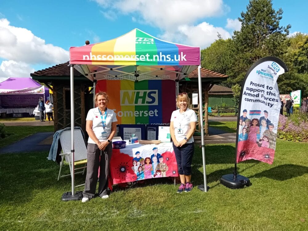 Rebecca Oliver and Teri Underwood from NHS Somerset's Armed Forces team standing under a gazebo at a community event