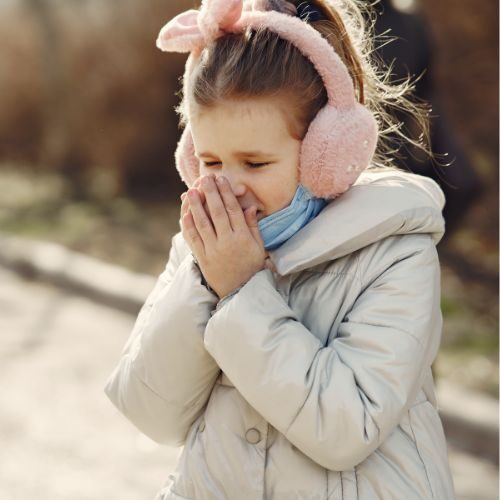 Young girl sneezing in winter
