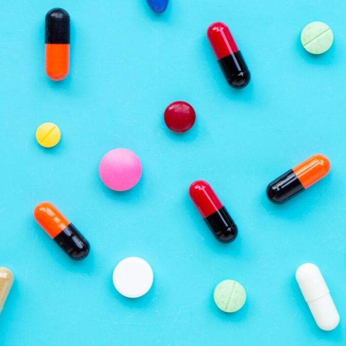 A variety of different tablets and capsules on a turquoise blue background