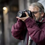 RS14572 Photograph of person stood taking pictures with a camera
