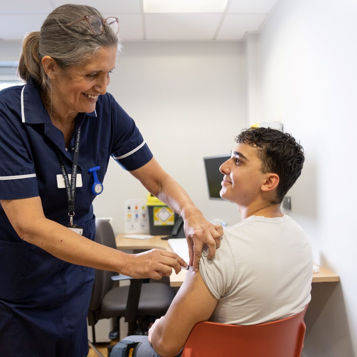 Photograph of person having an injection by a nurse in a consultation room